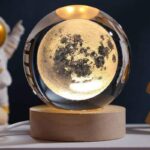 Lune en cristal optique représentant la surface lunaire, posée sur une base en bois, idéale pour la décoration scientifique et éducative.