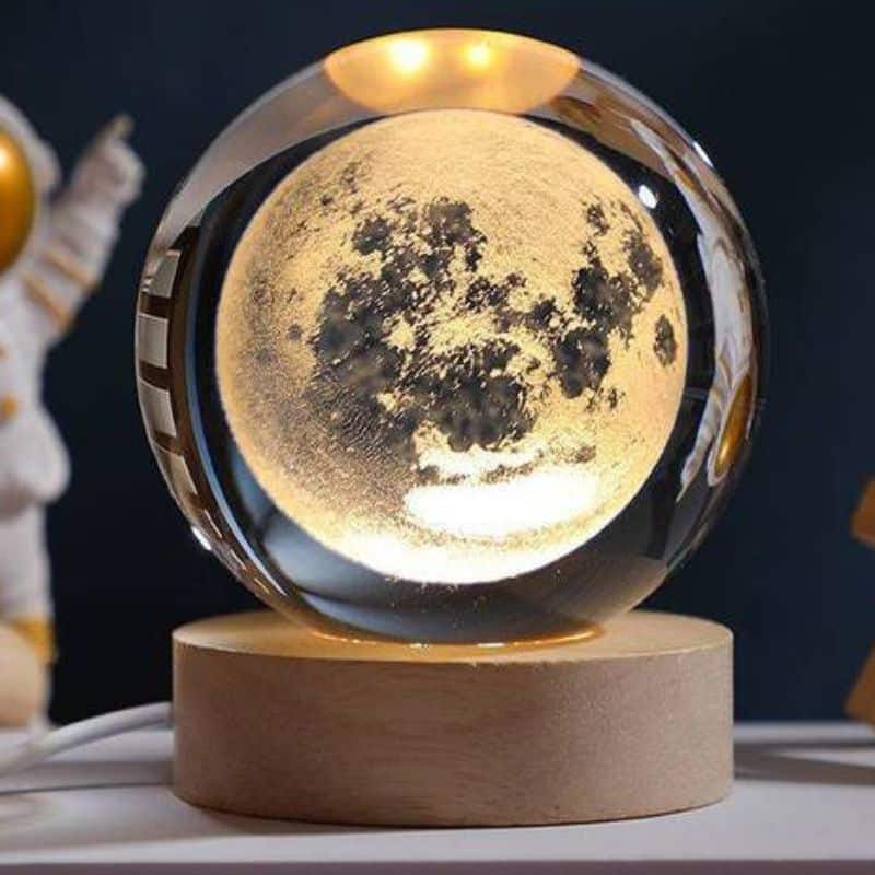 Lune en cristal optique représentant la surface lunaire, posée sur une base en bois, idéale pour la décoration scientifique et éducative.