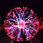Boule de plasma avec éclairs lumineux rouges et bleus, illustrant un phénomène électrique fascinant dans l'obscurité.