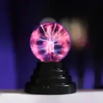 Pointe de décharge électrique visible avec éclairs lumineux violets et roses, illustrant un phénomène scientifique fascinant.