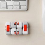 Cubes de puzzle mécanique pour bureau, conçus pour la décoration et la stimulation mentale, avec un design moderne en blanc et rouge, placé à côté d'un clavier d'ordinateur.