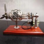 Réacteur scientifique miniature en métal avec tubes en verre et composants mécaniques, présenté sur un socle en bois pour décoration ou collection scientifique.