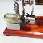 Pistolet à vapeur scientifique avec composants métalliques et verre, monté sur support en bois, utilisé pour expériences de physique ou chimie.
