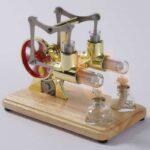 Modèle de machine à vapeur de laboratoire vintage avec tubes en verre et mécanisme en métal, posé sur une base en bois, illustrant un objet scientifique décoratif.