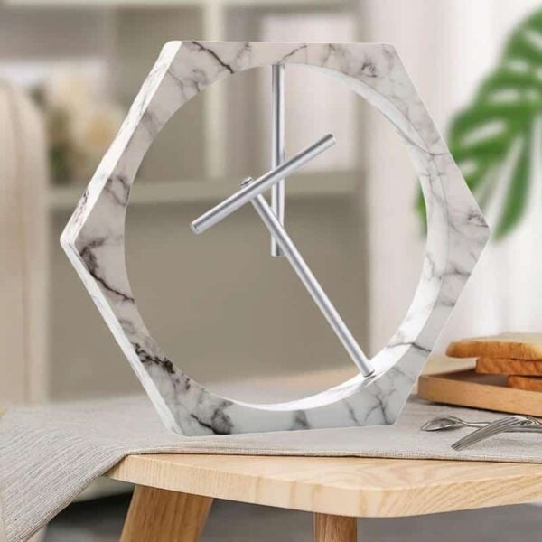 Horloge moderne en forme hexagonale avec cadre en marbre blanc et aiguilles en métal, idéale pour une décoration intérieure élégante et contemporaine.