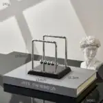 Pendentif Newton en métal, inspiré de la célèbre expérience de la boule de Newton, parfait pour la décoration de bureau ou d'étagère avec un style scientifique et moderne.