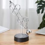 Balançoire de Newton en métal brillant avec sphère suspendue, idéale pour la décoration scientifique et éducative. Parfait pour un bureau ou une salle de classe, apportant une touche de curiosité et d.