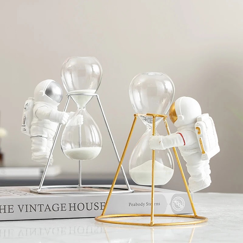 Réalisez une décoration originale avec ces figurines d'astronautes manipulant des sabliers en verre, symbolisant le temps et l'exploration spatiale.