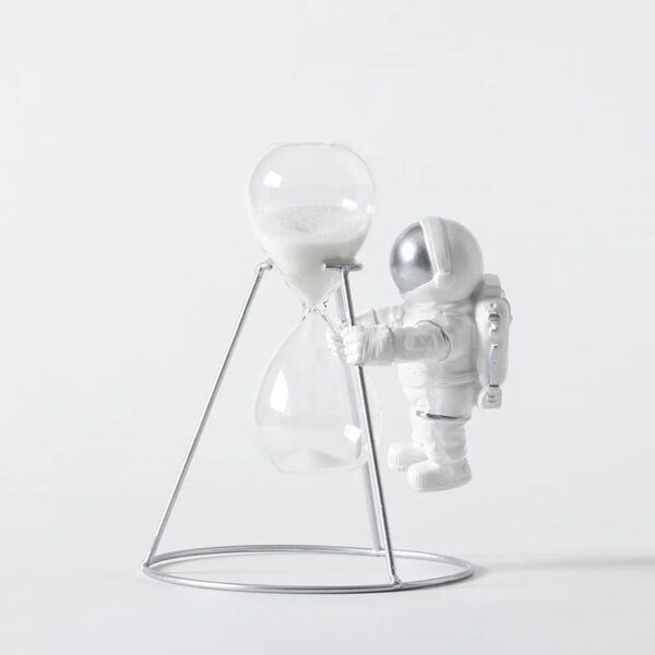 Sablier en verre avec support métallique, décor de style scientifique et spatial, représentant un astronaute en combinaison blanche manipulant un sablier.