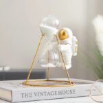 Objet scientifique décoratif en forme de sablier avec figurine d'astronaute.