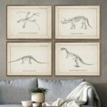 Quatre illustrations anciennes de squelettes de dinosaures, encadrées, accrochées au mur dans un salon moderne avec canapé gris et plante verte.