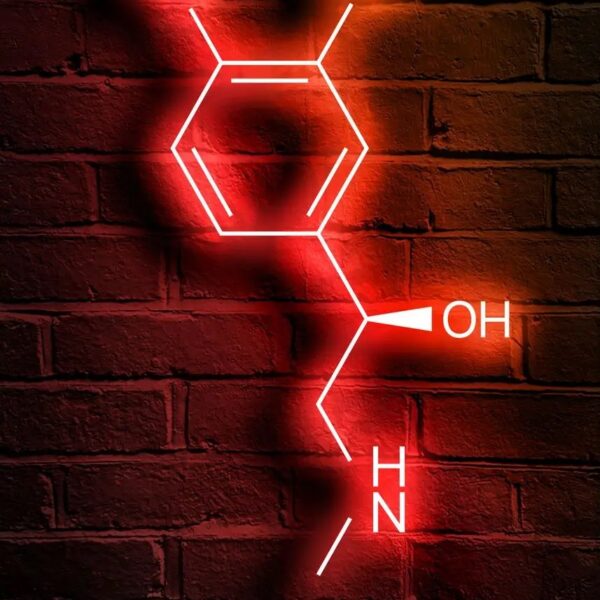 Illustration néon de la molécule de cocaïne en rouge sur un mur en briques, représentant la structure chimique avec ses groupes hydroxyle et amine.
