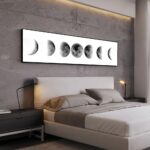 Illustration artistique de la lune avec différentes phases, suspendue au-dessus d'un lit contemporain dans une chambre élégante et minimaliste.