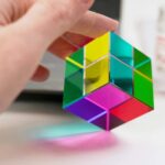 Cube en verre coloré avec surfaces réfléchissantes, utilisé comme objet de décoration scientifique ou pour des expériences optiques.