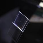 Plaque de plexiglas transparente avec reflets lumineux, utilisée pour des expériences scientifiques ou comme objet de décoration moderne.