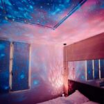 Projection d'étoiles et de galaxies sur le plafond et les murs d'une chambre, créant une ambiance cosmique relaxante et féerique.