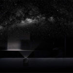 Projecteur de lumière créant une nébuleuse dans une pièce sombre, simulant un ciel étoilé avec des étoiles brillantes et une voie lactée.