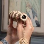 Viseur astronomique artisanal en bois, avec lentille et chaîne, utilisé pour l'observation céleste ou comme objet de décoration scientifique.
