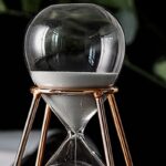 Sablier de laboratoire en verre avec support en métal cuivré, utilisé pour mesurer le temps dans les expériences scientifiques.