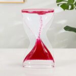 Sablier de laboratoire en verre transparent avec sable rouge, symbole du temps et de la science, idéal pour la décoration ou l'enseignement scientifique.