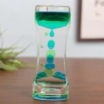 Vase en verre transparent contenant un liquide vert avec des bulles décoratives à l'intérieur, créant un effet visuel intéressant et moderne.