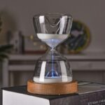 Sablier en verre avec lumière LED bleue, posé sur une base en bois, décoratif et scientifique, idéal pour la décoration intérieure ou comme objet de collection.