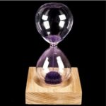 Sablier scientifique avec boule de fil métallique violet dans un cadre en bois, illustrant un objet de décoration scientifique unique.
