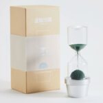 Sablier moderne avec plante verte dans un pot blanc, idéal pour la décoration scientifique et naturelle.