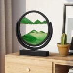 Objet décoratif en forme de cercle avec paysage en relief vert, posé sur une table en bois, avec un cactus en pot à côté, dans un intérieur moderne.