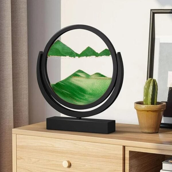 Objet décoratif en forme de cercle avec paysage en relief vert, posé sur une table en bois, avec un cactus en pot à côté, dans un intérieur moderne.