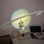 Saturne projetée sur le mur avec ombre de plantes et décorations de bureau.