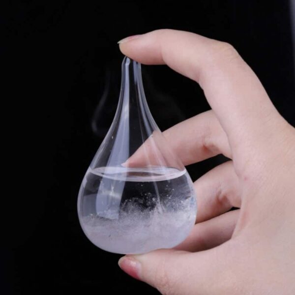 Pipette en verre contenant un liquide vaporisé, tenue par une main contre un fond noir, illustrant une expérience scientifique ou une démonstration de laboratoire.