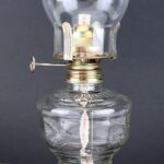 Lampe à pétrole vintage en verre avec mécanisme en métal, idéale pour décoration scientifique ou rétro.
