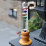 Boule de Newton avec pendules en verre colorés et support en bois, illustrant un dispositif scientifique classique pour démonstration de la conservation de l'énergie.