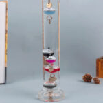 Boule à neige scientifique contenant des anneaux métalliques suspendus dans un liquide clair, utilisée comme décoration éducative ou de bureau.