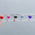 Bâtonnets transparents avec liquides colorés en suspension, utilisés pour des expériences scientifiques ou la décoration.