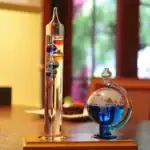 Dispositifs de laboratoire en verre avec liquide coloré, comprenant un pied à eau vertical et un ballon de distillation sphérique, utilisés pour des expériences scientifiques.