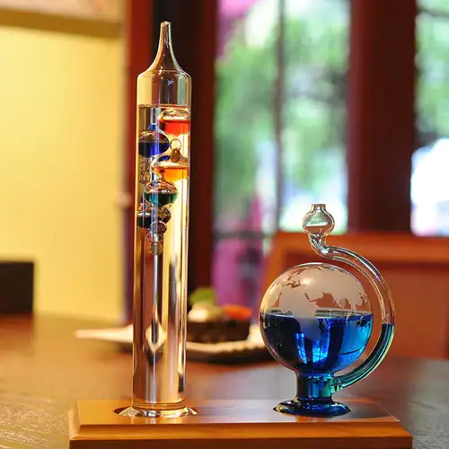 Dispositifs de laboratoire en verre avec liquide coloré, comprenant un pied à eau vertical et un ballon de distillation sphérique, utilisés pour des expériences scientifiques.