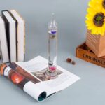Vase en verre avec liquide coloré, livres de science et décorations, parfait pour une décoration scientifique ou éducative.