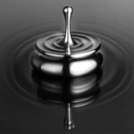 Pendentif en acier inoxydable brillant flottant sur l'eau, créant un effet de reflet et de mouvement. Parfait pour la décoration ou comme accessoire scientifique élégant.
