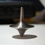Toupie en métal inoxydable, objet de décoration scientifique, illustrant la physique et la dynamique. Parfaite pour une décoration moderne ou un collectionneur d'objets scientifiques.