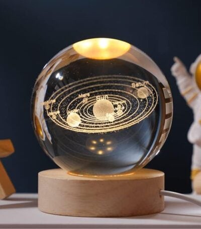 Sphere en cristal représentant le système solaire avec planètes et orbites gravées, posée sur un socle en bois, idéale pour la décoration scientifique et éducative.