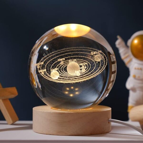 Sphere en cristal représentant le système solaire avec planètes et orbites gravées, posée sur un socle en bois, idéale pour la décoration scientifique et éducative.