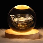 Représentation du système solaire en boule de verre avec planètes et orbites gravitant autour du Soleil, illuminée pour un effet visuel captivant.