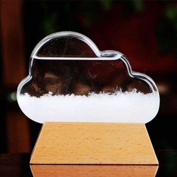 Nuage en verre transparent avec neige artificielle à l'intérieur, posé sur une base en bois, illustrant un phénomène météorologique miniature.