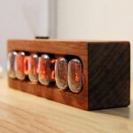 Puce de Nixie dans un boîtier en bois, utilisée comme décoration vintage ou objet scientifique, avec des chiffres lumineux orange. Parfait pour une ambiance rétro et technologique.