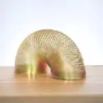 Sculpture en spirale dorée en métal, design moderne et artistique, posée sur une surface en bois clair, idéale pour la décoration scientifique ou contemporaine.