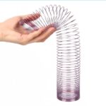 Pendentif en spirale métallique tenu par une main, illustrant un objet scientifique pour expériences ou décoration.