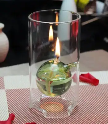 Porte-bougie en verre contenant une bougie allumée, idéal pour la décoration scientifique ou de laboratoire.