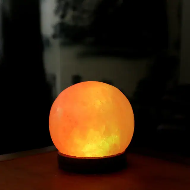 Lampe de lune en sel de l'Himalaya émettant une lumière chaleureuse, idéale pour la décoration intérieure ou comme veilleuse relaxante.